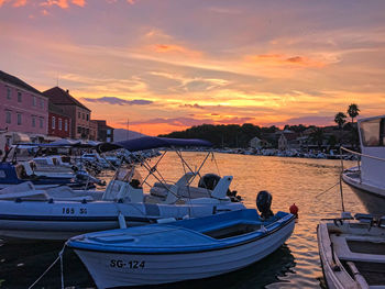 Sailboats moored at harbor during sunset