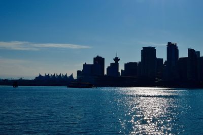 City at waterfront against blue sky