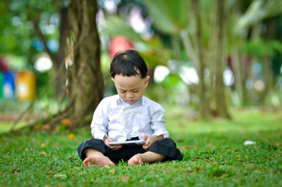 Boy looking away while sitting on grass