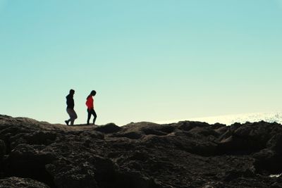 Men standing on rock against sky