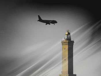 Low angle view of airplane flying over building against sky