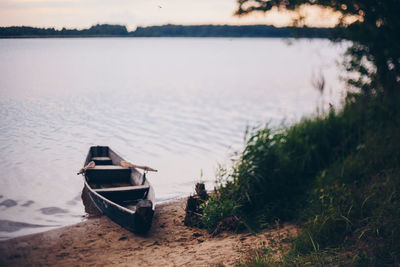 Boat moored on shore by lake