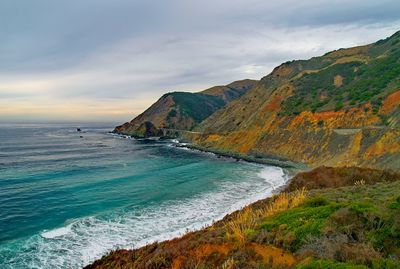 Scenic view of sea by mountains against sky