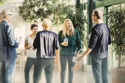 Cheerful businesswoman with colleagues having casual meeting in creative office