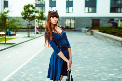 Full length portrait of young woman standing in city