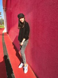 Portrait of woman standing against red wall