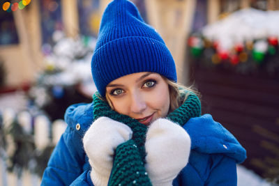 Woman in blue jacket and green scarf and white gloves in winter. square in moscow on christmas day