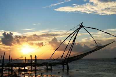 Silhouette sailboats in sea against sky during sunset