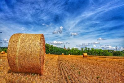 Hay bales on field against sky