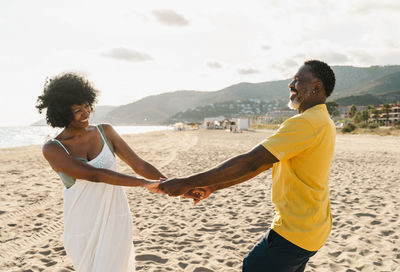 Side view of couple standing at beach