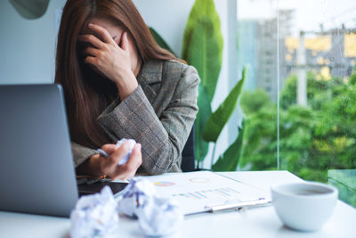 Midsection of woman using mobile phone while sitting on table