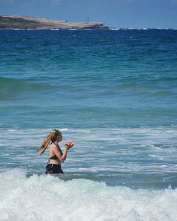 Woman in sea against blue sky