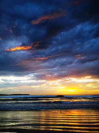 Scenic view of sea against dramatic sky during sunset