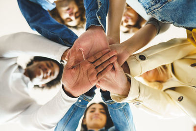 Low angle view of friends keeping hands on top each other