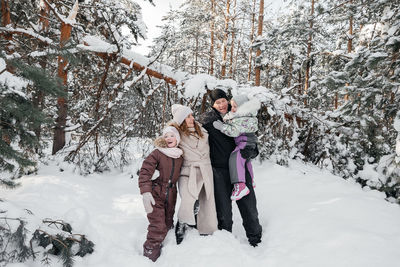 Dad and mom and daughters have fun in the snowy forest. high quality photo
