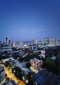 High angle view of buildings in city against blue sky