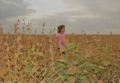 Girl standing on field against sky