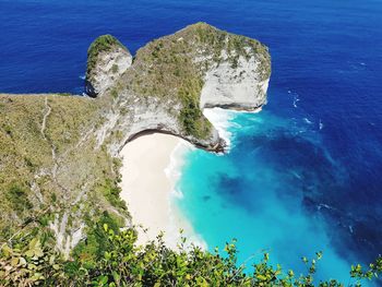 High angle view of rocks by sea against blue sky