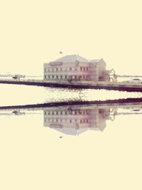 Reflection of built structure in water against clear sky