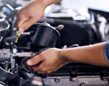 Cropped hands of mechanic repairing car