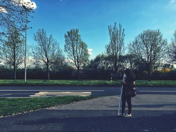 Woman standing on road against trees