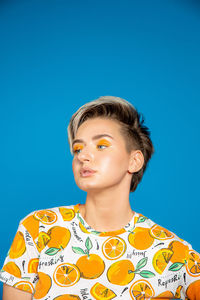 Portrait of teenage boy looking away against blue background