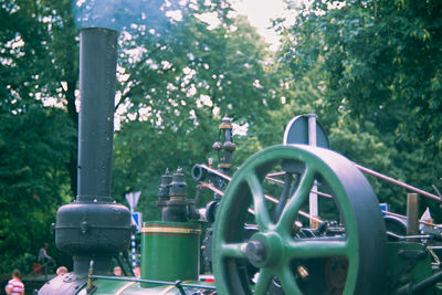 Close-up of machine part by trees