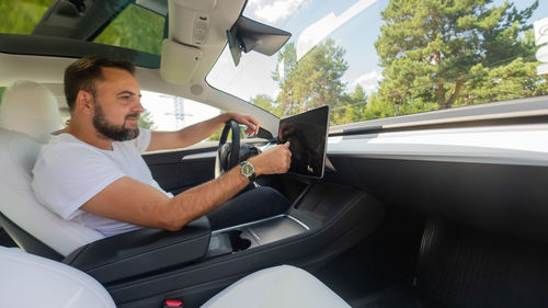 Side view of man using mobile phone while sitting in car