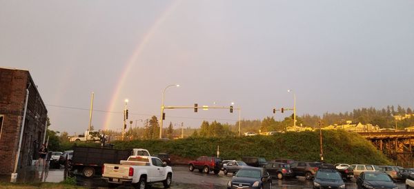 Cars on street against rainbow in city