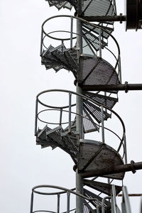 Low angle view of metallic spiral staircase against clear sky