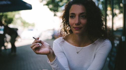 Woman smoking while sitting at sidewalk cafe