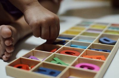 Close-up of child playing with colorful alphabet toys in box