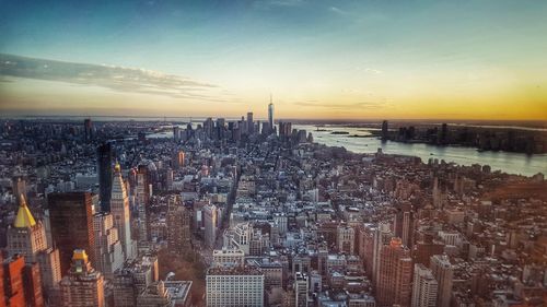 Aerial view of city at waterfront during sunset