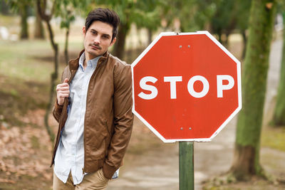 Portrait of young man standing by stop sign