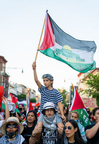 Portrait of people with flag in traditional clothing against sky