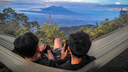 Rear view of people looking at mountains against sky