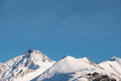 Low angle view of snow against clear blue sky