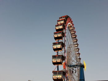 Low angle view of ferris wheel against clear blue sky