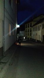 People walking on illuminated street amidst buildings in city at night