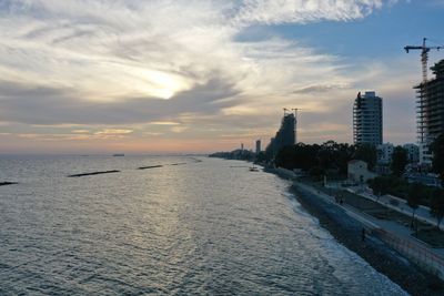 Scenic view of sea by buildings against sky during sunset