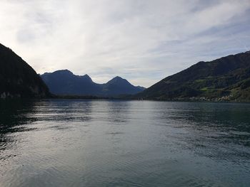 Scenic view of lake by mountains against sky