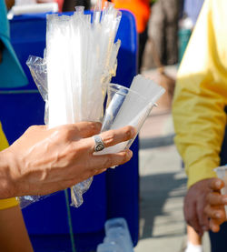 Cropped image of man holding disposable glass and straws outdoors