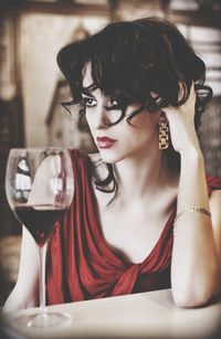 Beautiful woman sitting by red wine in restaurant