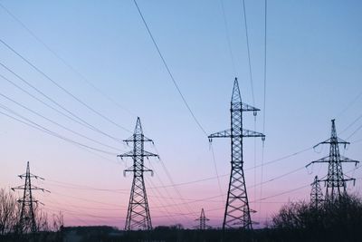 Low angle view of silhouette electricity pylon against sky