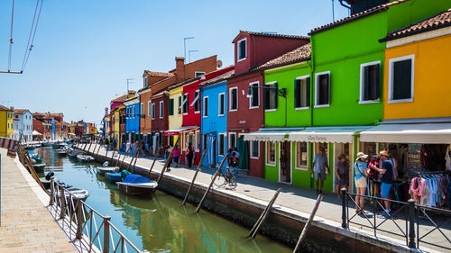 Boats in canal by buildings against clear sky