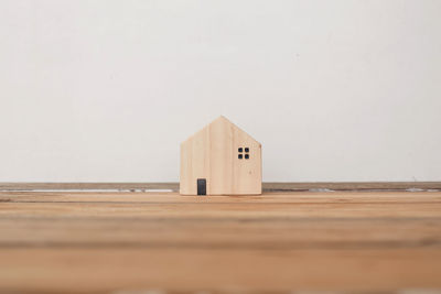 Close-up of wooden structure on table against white wall