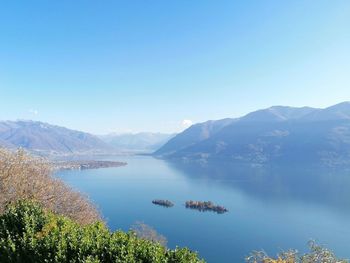 Scenic view of lake and mountains against clear blue sky