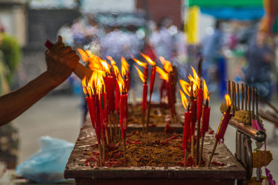 Cropped hand igniting incense at temple