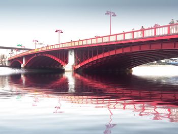 Bridge over river against sky in city