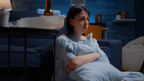 Young woman sitting on bed at home